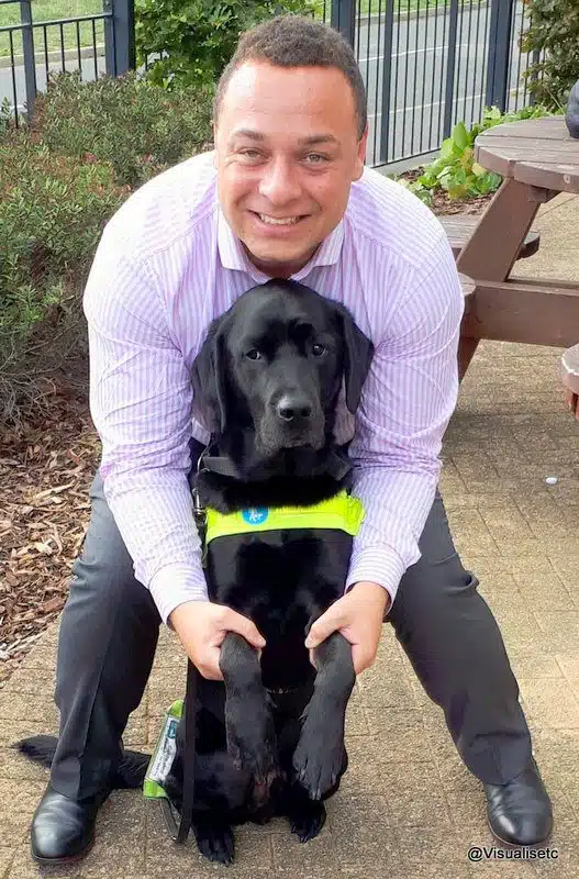20180918 151539 2 2 Zodiac - A Blind Man’s Best Friend Dan and his best friend Zodiac. Dan is smiling and holding his black lab's paws